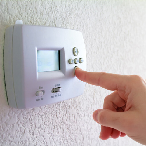 finger pressing a thermostat