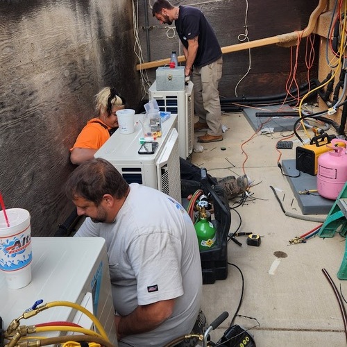 technicians replacing air conditioning parts